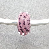 Pink mauve glass bead with inner detail on a silver bangle on a grey background