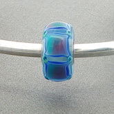 Blue glass bead with squares on a silver bangle against a grey background