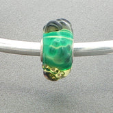 Green glass bead with tactile paw prints on a silver bangle against a grey background