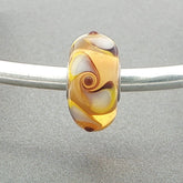 Murano glass bead with spinner pattern on a silver bangle against a grey background