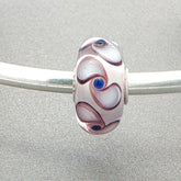 Murano glass bead with white core and spinner pattern on a silver bangle against a grey background