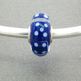 Murano glass bead with blue core and blue dice design on a silver bangle against a grey background