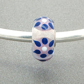 Decorative glass bead with blue sun rays type design on a silver bangle against a grey background