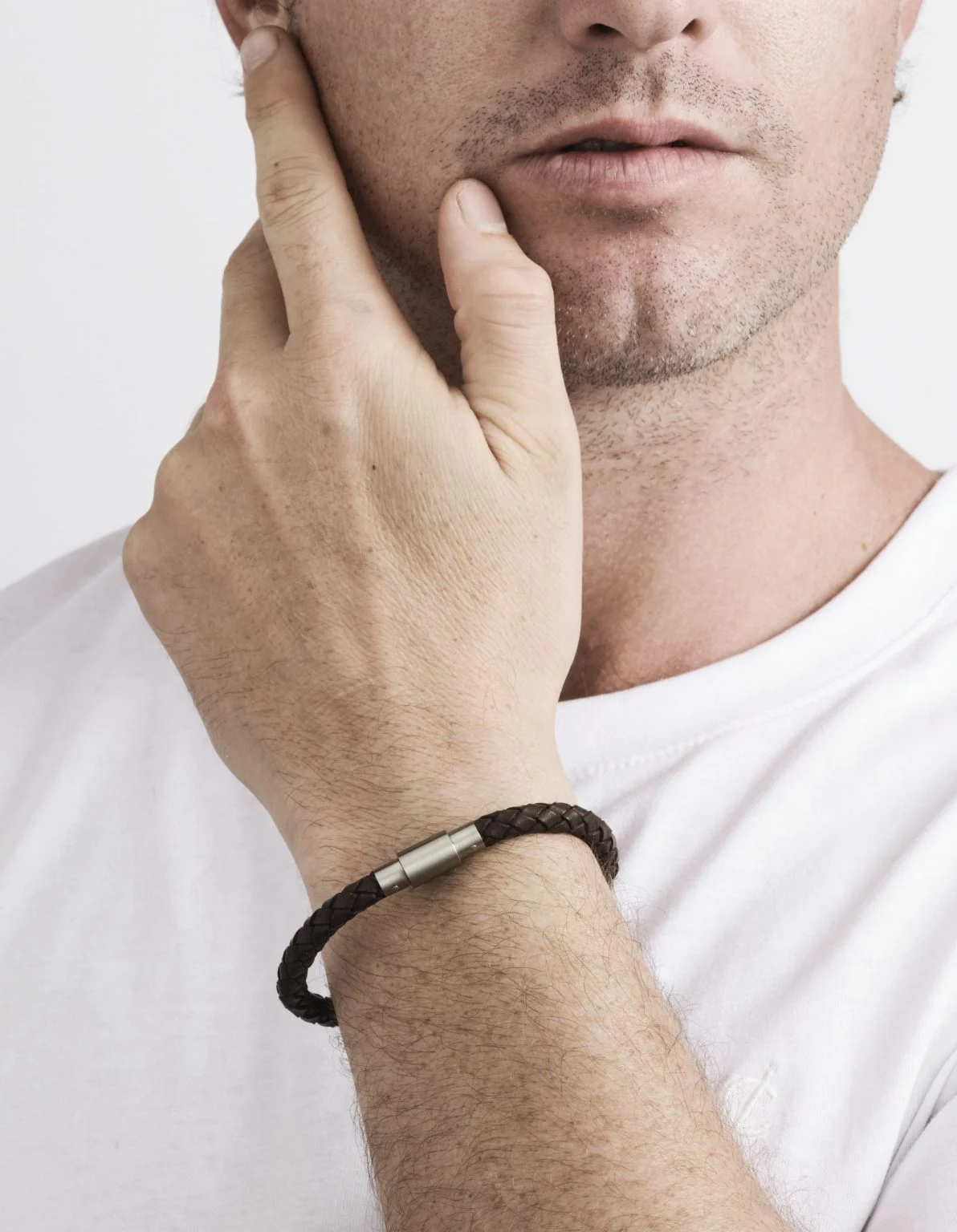Man wearing a black bracelet on his wrist with a plain background