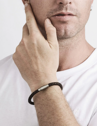 Man wearing a black bracelet on his wrist with a plain background
