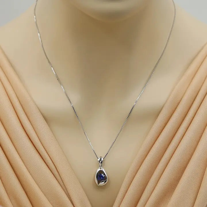 Silver necklace with a pendant on a mannequin wearing a beige dress.