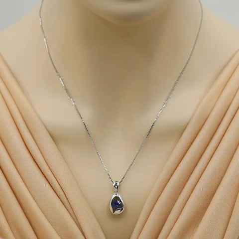 Silver necklace with a pendant on a mannequin wearing a beige dress.