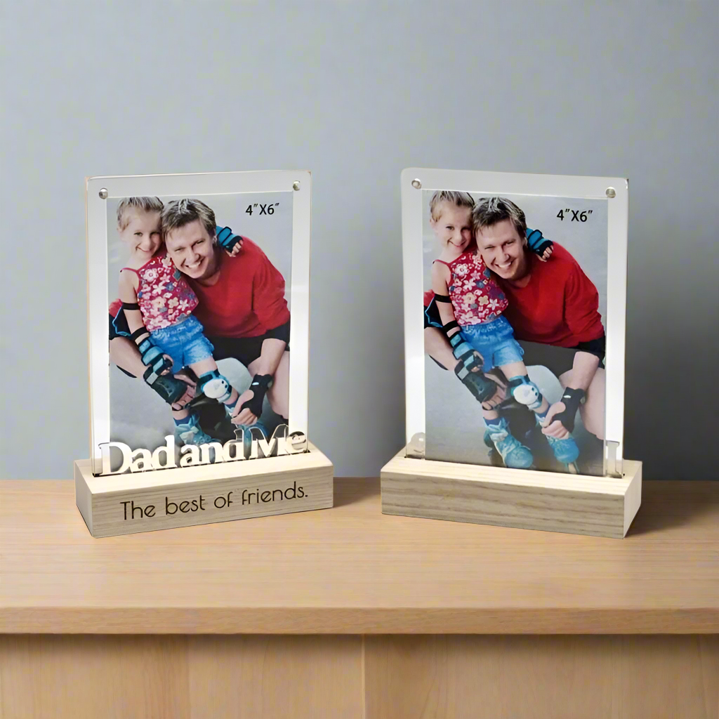 Two photo frames with a picture of a father and child, placed on a wooden surface.