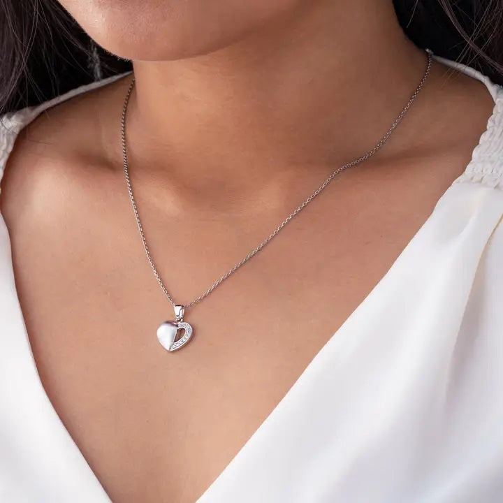 Silver heart-shaped necklace on a person wearing a white top