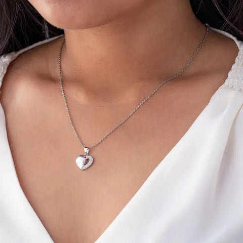 Silver heart-shaped necklace on a person wearing a white top