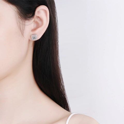 Close-up of a person wearing a pink moissanite square earring on a plain background