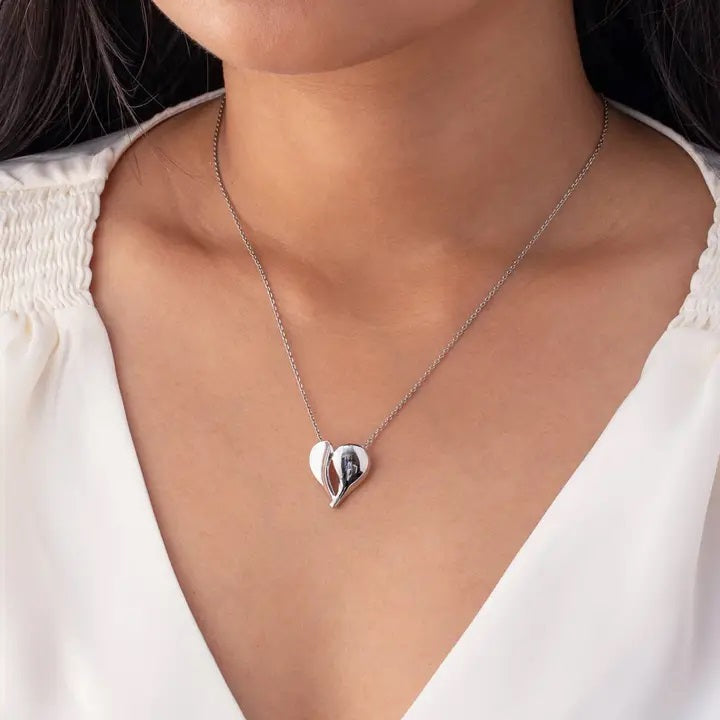 Silver heart-shaped necklace on a person wearing a white top