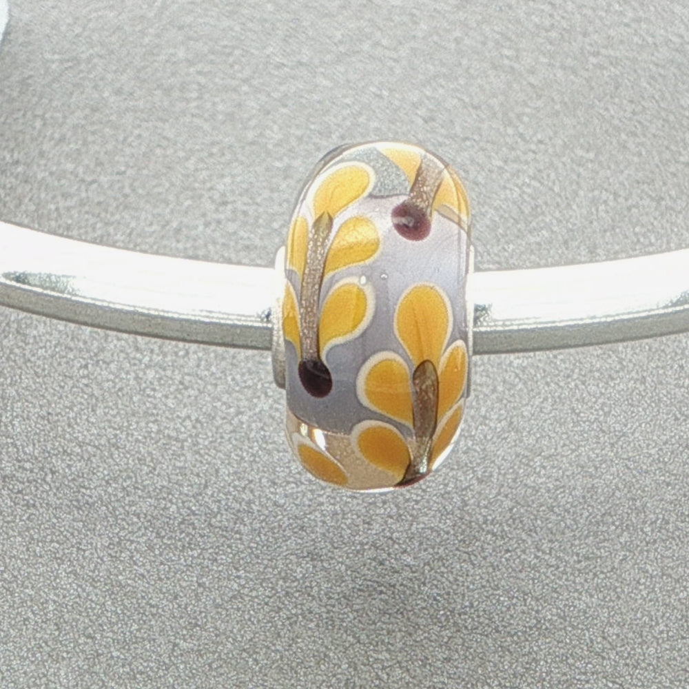 Silver bangle with a leafy designed murano glass bead against a grey background