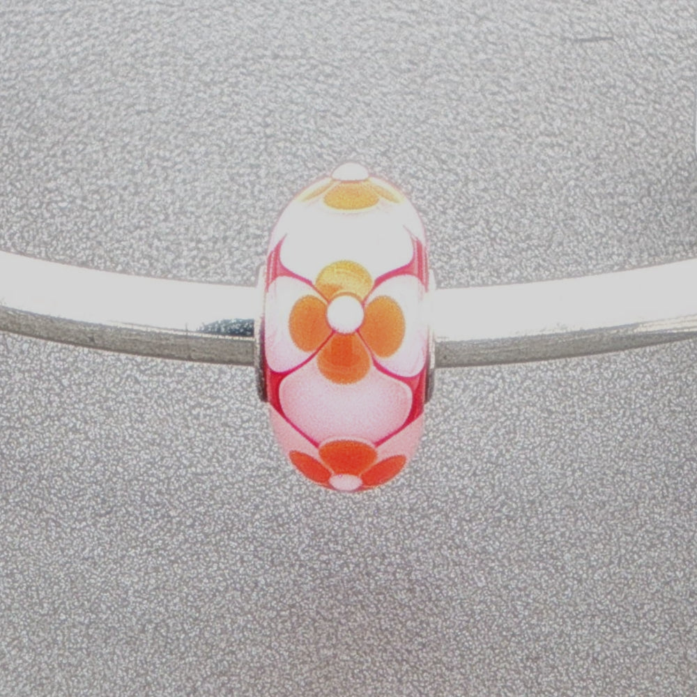 Floral murano glass bead on a silver bangle against a grey background