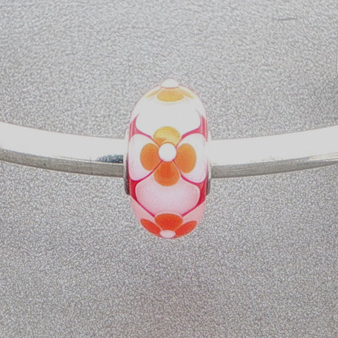 Floral murano glass bead on a silver bangle against a grey background