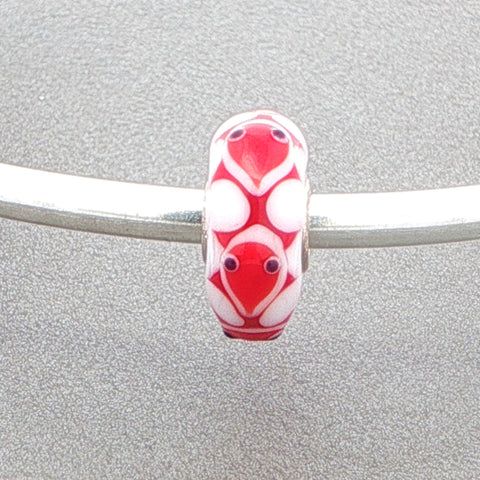Red and white glass bead with a cute animal face design on a silver bangle against a grey background