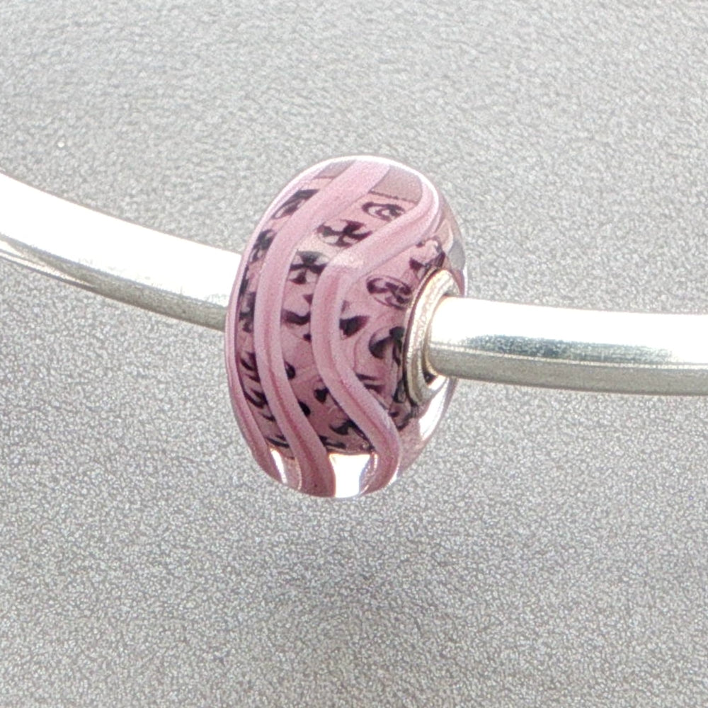 Pink mauve glass bead with inner detail on a silver bangle on a grey background