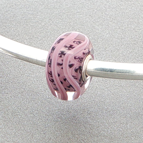 Pink mauve glass bead with inner detail on a silver bangle on a grey background