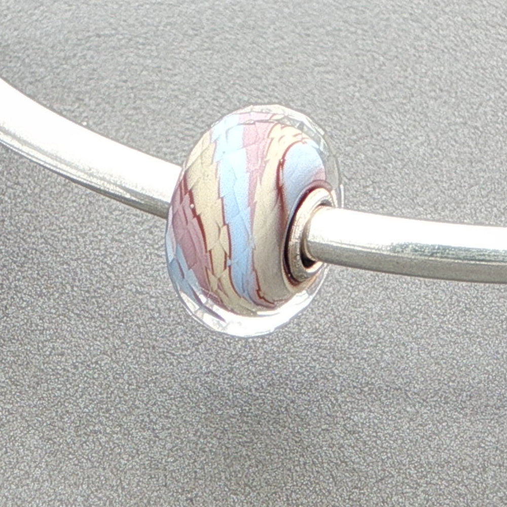Silver bangle with a marbled glass bead on a grey background