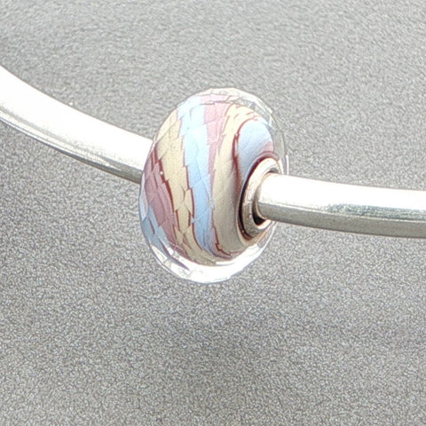 Silver bangle with a marbled glass bead on a grey background