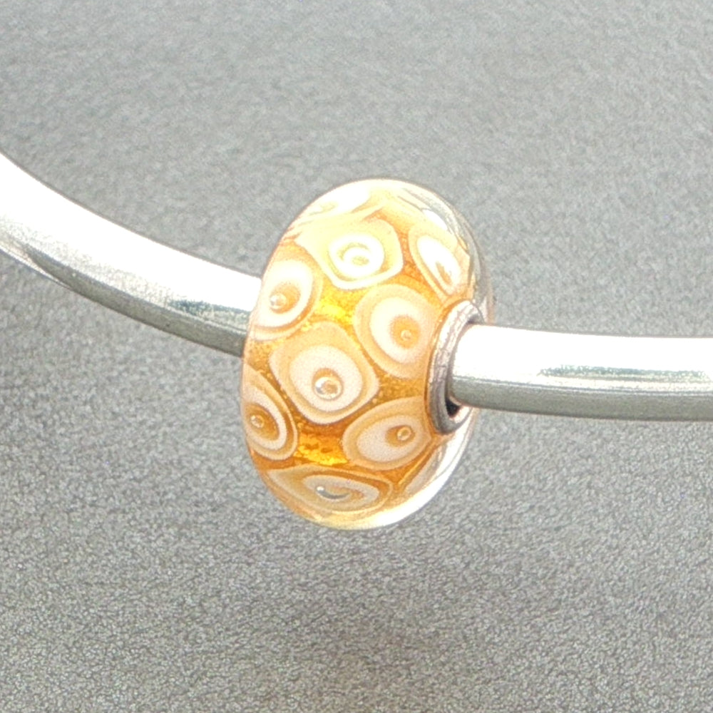 honeycomb design bead on a silver bangle on a grey background