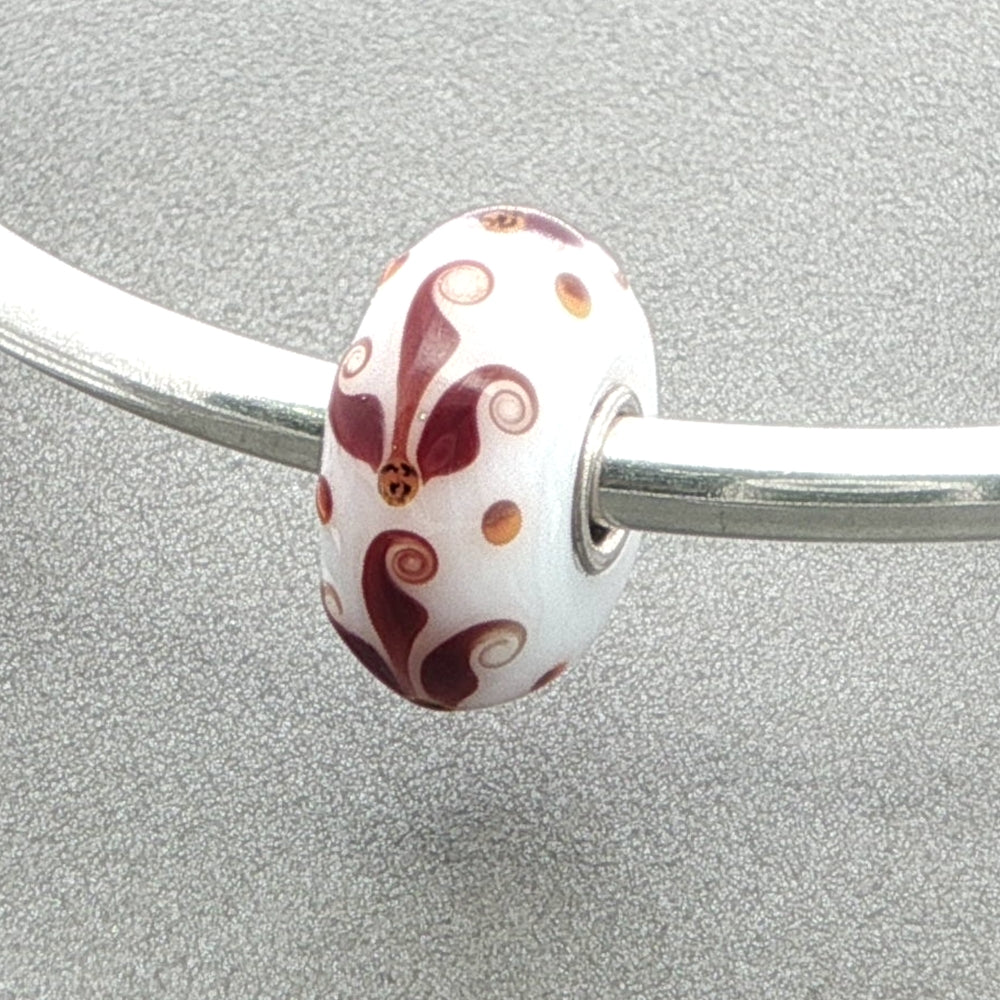 Silver bangle with a white opaque glass bead against a grey background