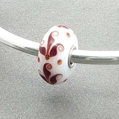 Silver bangle with a white opaque glass bead against a grey background
