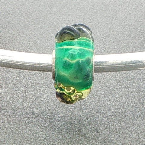 Green glass bead with tactile paw prints on a silver bangle against a grey background