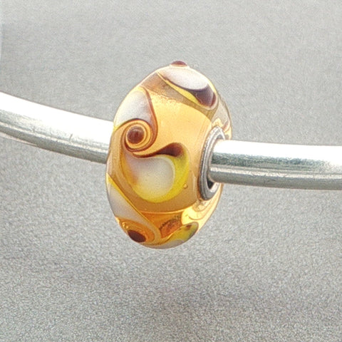 Glass bead with spinner pattern on a silver bangle against a grey background