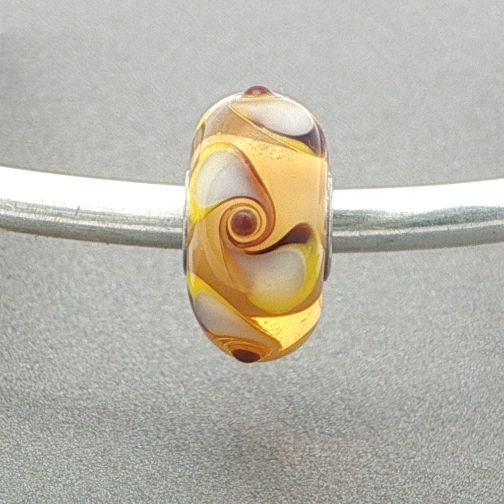 Murano glass bead with spinner pattern on a silver bangle against a grey background